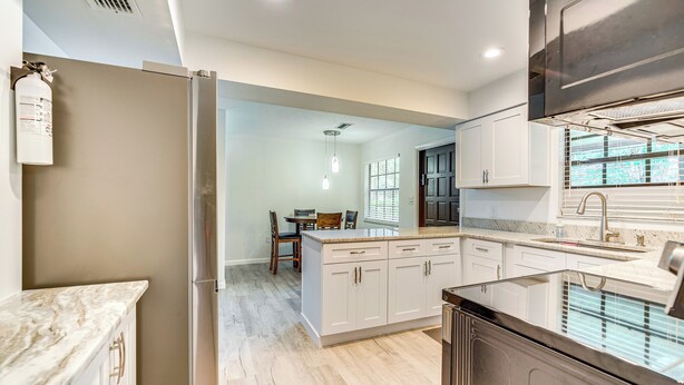 Una cocina moderna con armarios blancos, una isla integrada y un refrigerador de acero inoxidable.