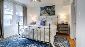 A bedroom with a bed, a ceiling fan, a painting, bedside lamps, and a nightstand. - 4 Mi to Dtwn: Baton Rouge Bungalow w/ Private Yard (Baton Rouge)