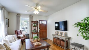 A living room with a sofa, armchair, wooden coffee table, TV, and a plant. - 4 Mi to Dtwn: Baton Rouge Bungalow w/ Private Yard (Baton Rouge)