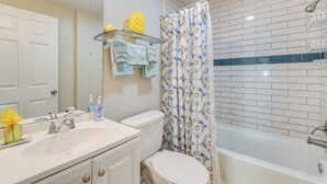 A bathroom with a white sink, toilet, and bathtub. There is a shower curtain with a blue and white pattern, and a mirror above the sink. - 1 Mi to Dtwn: Home w/ Furnished Patio in Pensacola (Pensacola)