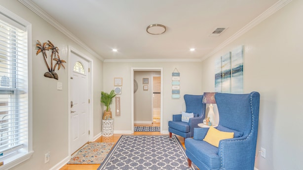 A hallway with a blue armchair, a patterned rug, and a decorative wall piece. - 1 Mi to Dtwn: Home w/ Furnished Patio in Pensacola (Pensacola)