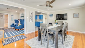 A modern living room with a dining area, a kitchen, and a TV mounted on the wall. - 1 Mi to Dtwn: Home w/ Furnished Patio in Pensacola (Pensacola)