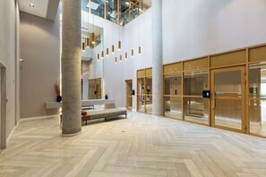 A spacious lobby with a herringbone floor, a central seating area, and large glass doors leading to another space. - 360 SP Perdizes Turiassu (São Paulo)