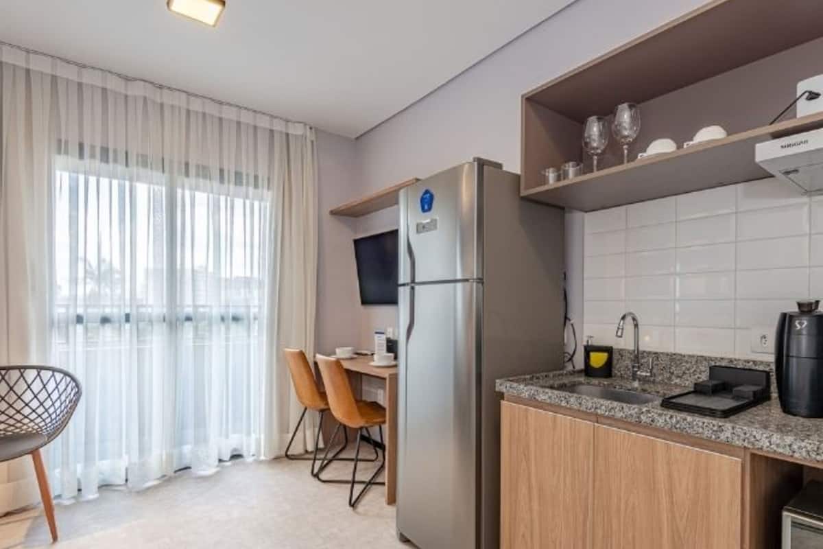 A modern kitchen with a built-in refrigerator, a granite countertop, and a coffee machine.
