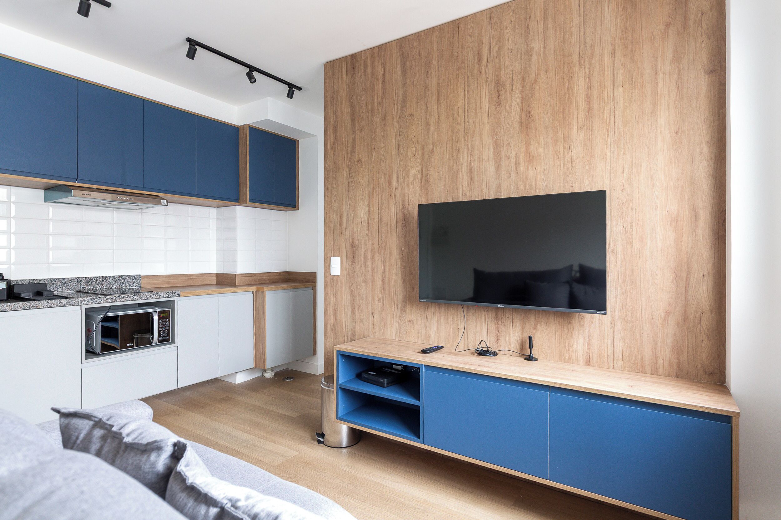 A modern kitchen with built-in appliances, a flat-screen TV, and a seating area with a sofa.