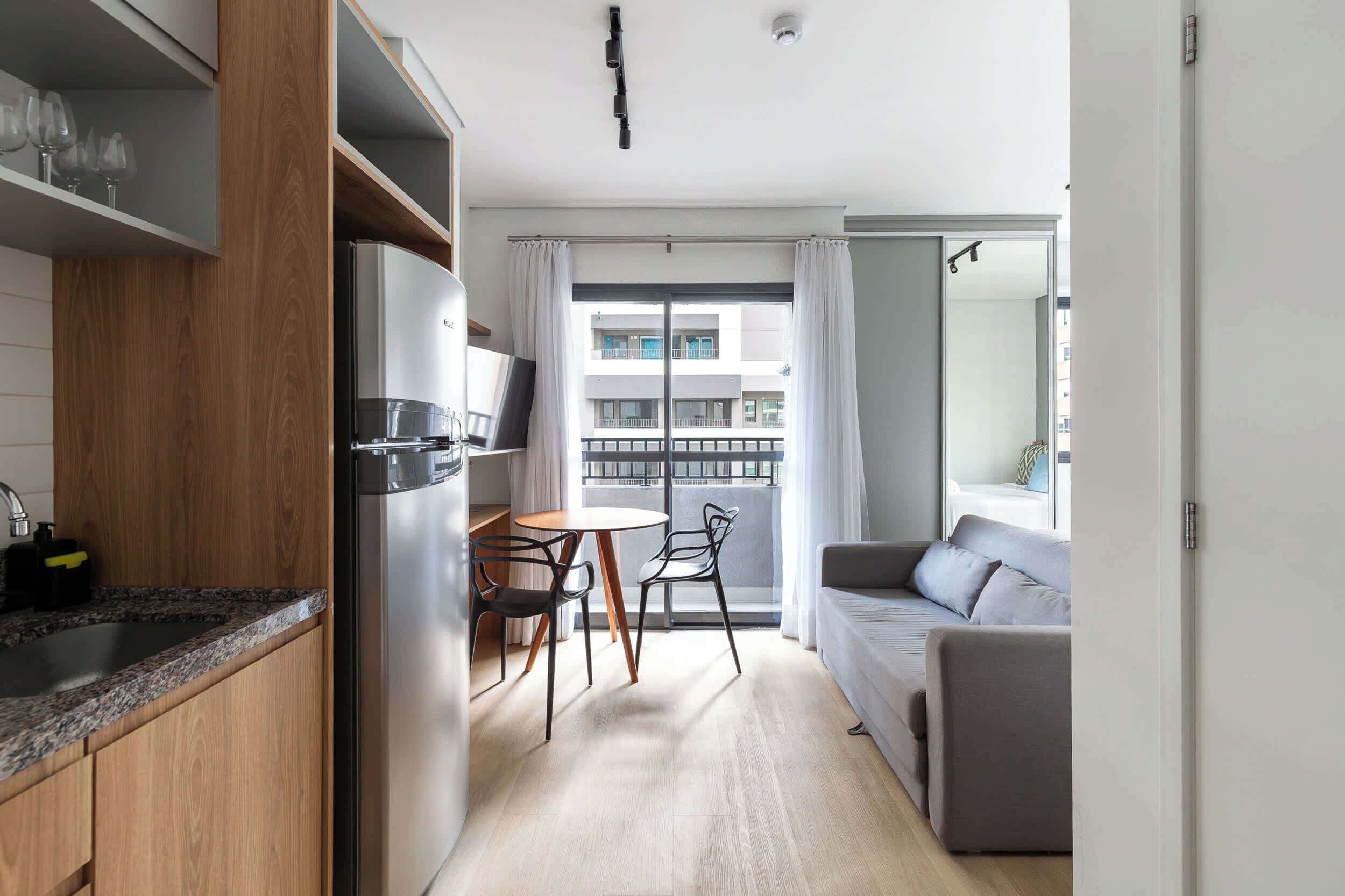 A compact living space with a kitchenette, a dining area, and a seating area with a view of the building outside.