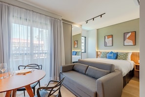 A modern hotel room with a bed, sofa, dining table, and chairs. - 360 SP Perdizes Turiassu (São Paulo)
