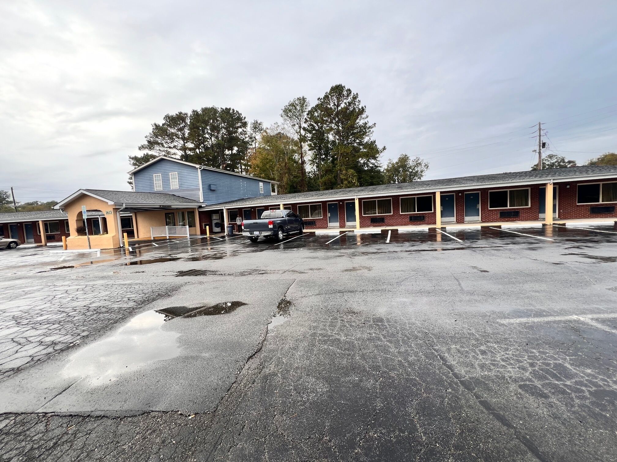 A motel with a parking lot, a blue building, and a truck parked in the lot.