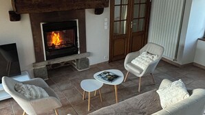 A living room with a fireplace, a sofa, two armchairs, and a small table. - Charming and spacious Breton house (Jugon-les-Lacs)