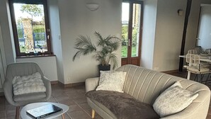 A spacious living room with a sofa, armchair, and coffee table. - Charming and spacious Breton house (Jugon-les-Lacs)