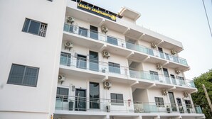 A multi-story building with balconies, air conditioning units, and a sign reading "Legacy Apartments." - Legacy Apartments Phase 4 (Serrekunda)
