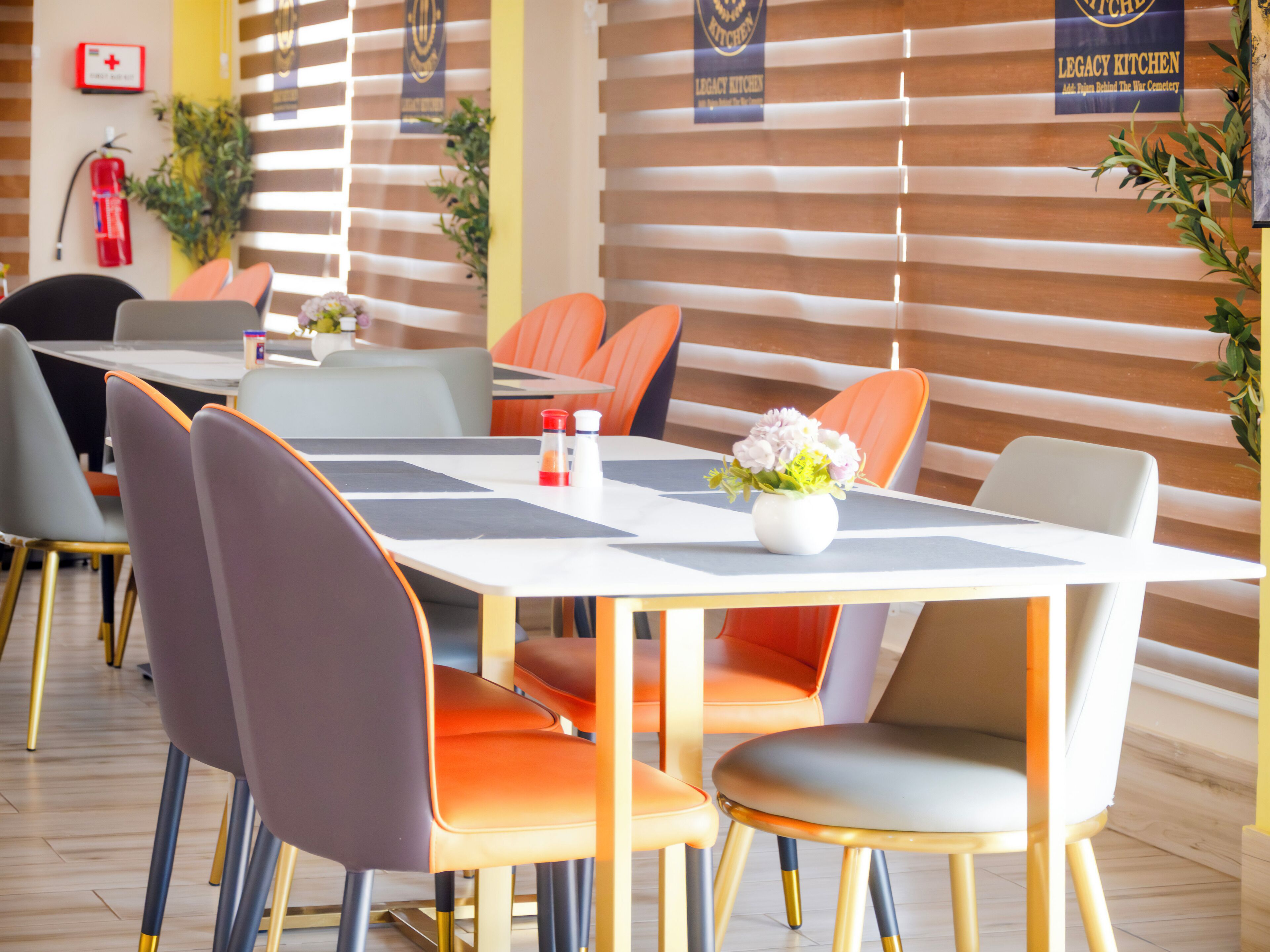 A dining area with tables and chairs, a vase with flowers, and a fire extinguisher on the wall.