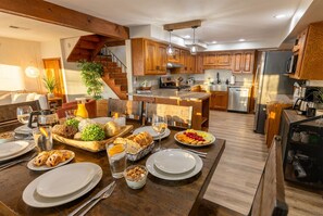 A modern kitchen with wooden cabinets, a central island, and a dining area set for a meal.