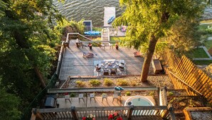 Una terraza de madera con mobiliario exterior, una bañera de hidromasaje y vistas a un cuerpo de agua.