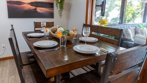 Una mesa de comedor de madera con platos, vasos y un centro de mesa con frutas y frutos secos.