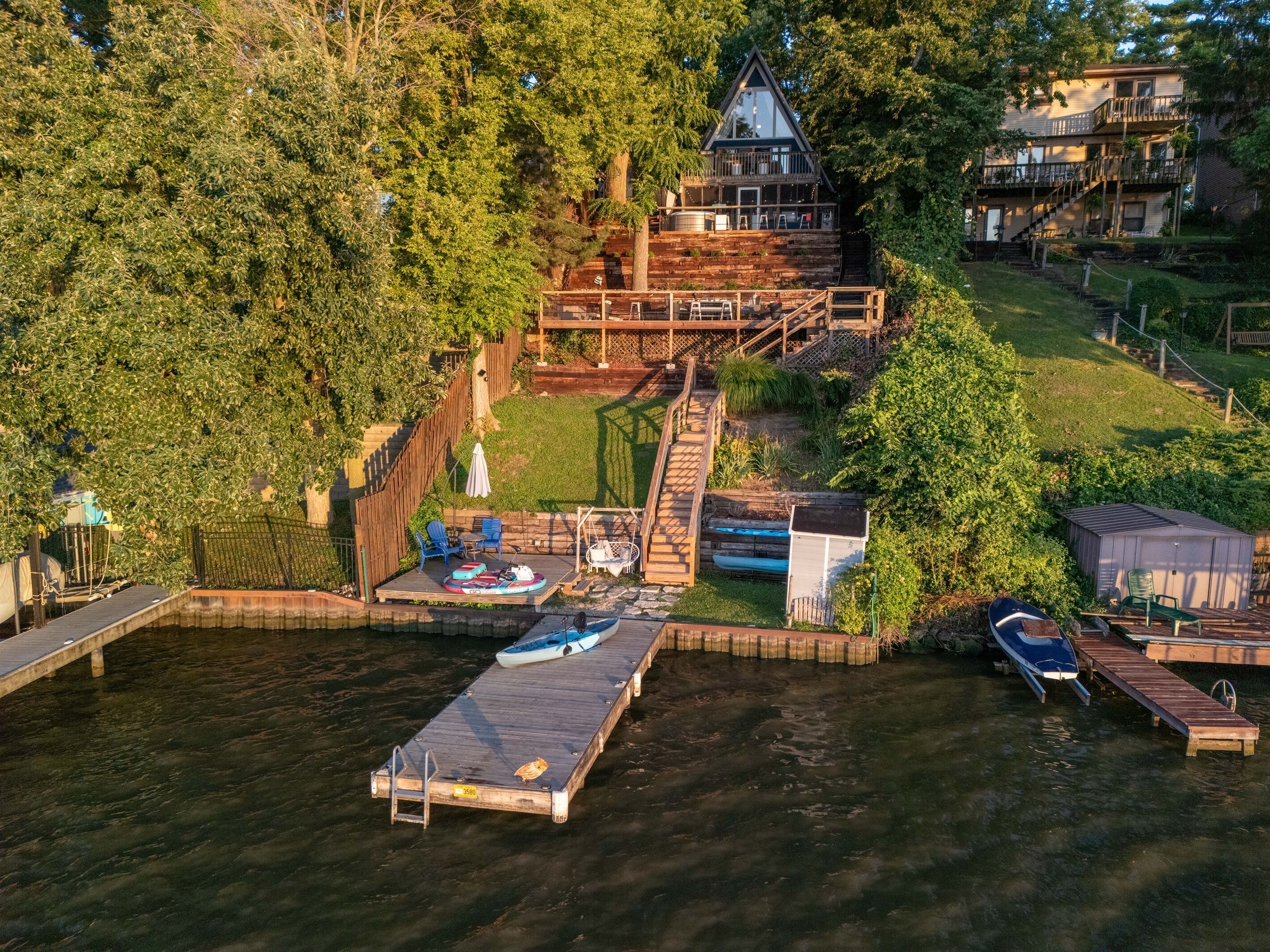 Un muelle de madera con barcos, un cobertizo pequeño y una casa con balcón.
