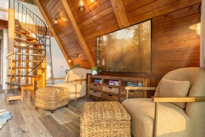 A cozy living room with a wooden staircase, comfortable seating, and a large window.