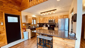 A modern kitchen with wooden cabinets, stainless steel appliances, and a central island with bar stools.