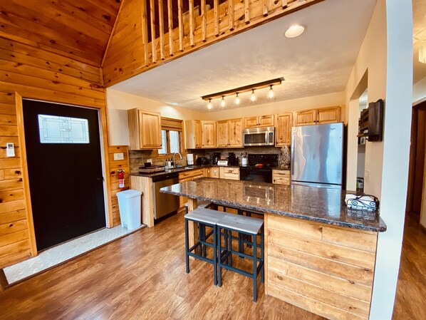 A modern kitchen with wooden cabinets, stainless steel appliances, and a central island with bar stools.