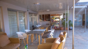A covered outdoor seating area with wicker furniture, tables, and chairs.