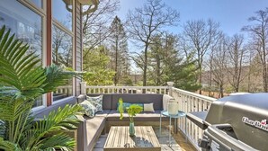 A deck with a sofa, a table, and a grill.