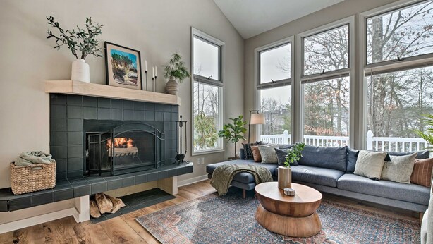 A living room with a fireplace, large windows, a sofa, and a coffee table.
