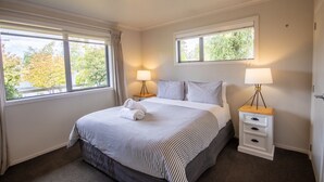 A neatly arranged bedroom with a bed, two bedside tables, and two lamps. - Ultimate Escape in Twizel (Twizel)
