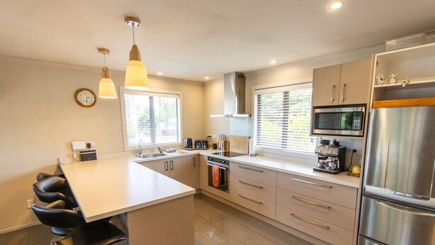 A modern kitchen with a central island, stainless steel appliances, and pendant lighting. - Ultimate Escape in Twizel (Twizel)