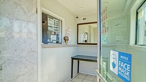 A hotel reception area with a marble wall, a reception desk, and a 'Face Mask Required' sign. - Super 7 Inn By Oyo San Antonio N.W. Medical Center (San Antonio)