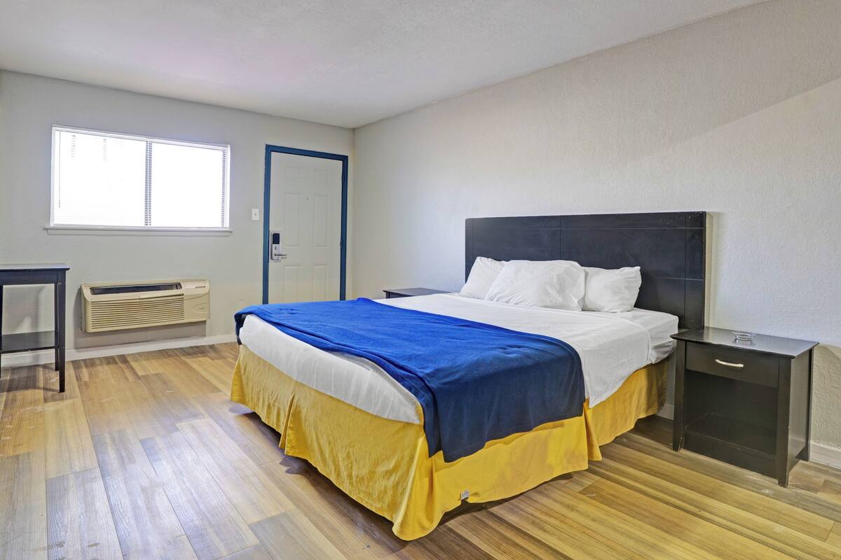A bedroom with a bed, bedside table, and a window.