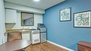 A compact kitchen with a dining table, a microwave, a refrigerator, and a stove. - Super 7 Inn By Oyo San Antonio N.W. Medical Center (San Antonio)