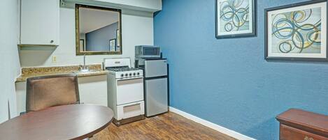 A compact kitchen with a dining table, a microwave, a refrigerator, and a stove.