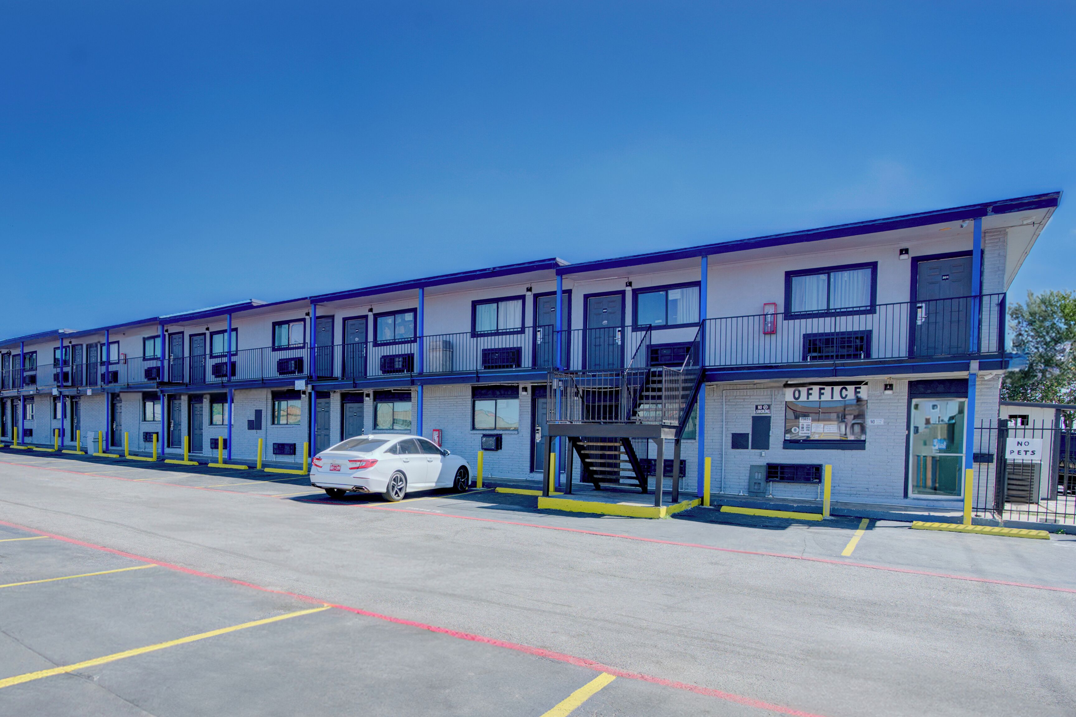 A row of motel buildings with a white car parked in front.
