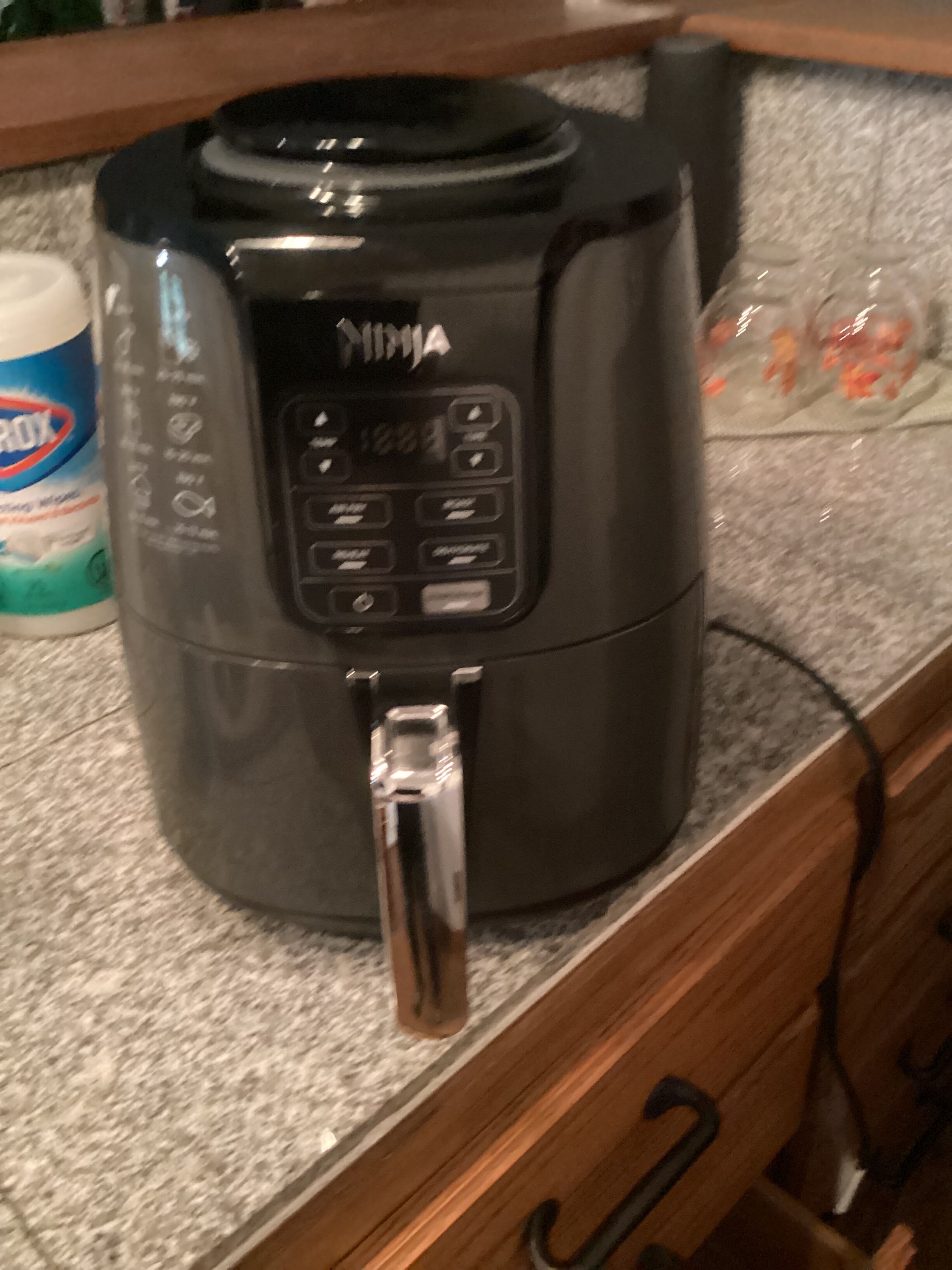 Una cocina con cafetera, una botella de detergente y una bolsa de comida en la encimera.
