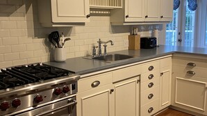 Een keuken met witte kastjes, een roestvrijstalen fornuis en een houten aanrecht.