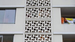 A building with a patterned facade, a central entrance with a door, and a small outdoor area with a railing. - Écrin de Lumière in Vienna (Vienne)
