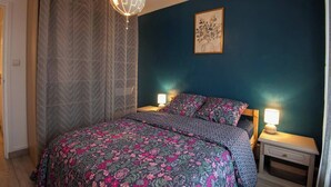 A bedroom with a large bed, two bedside tables, a globe light, and a floral painting on the wall. - Écrin de Lumière in Vienna (Vienne)
