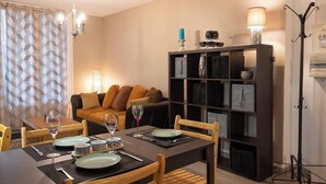 A dining area with a table set for two, a sofa, and a bookshelf. - Écrin de Lumière in Vienna (Vienne)