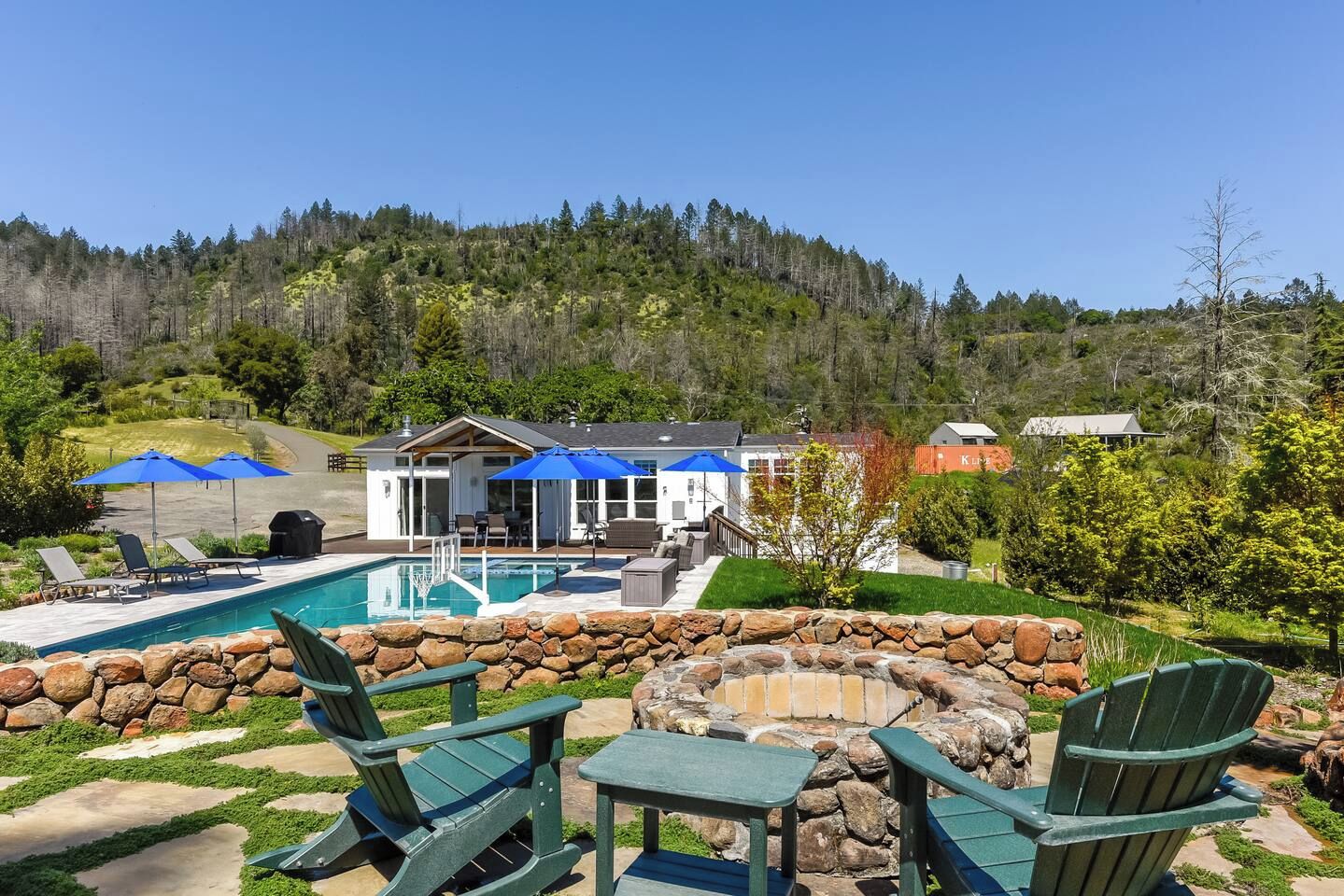 Ein Wohnhaus mit Swimmingpool, Sitzgelegenheit im Freien und einer Steinmauer.