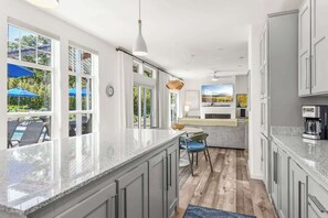 Une cuisine moderne dotée d’un grand îlot central, de meubles de couleur grise et offrant une vue sur l’extérieur.