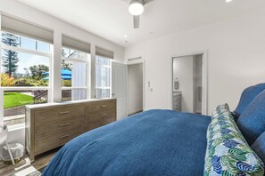 Ein Schlafzimmer mit einem großen Bett, einem Schminktisch, einem begehbaren Kleiderschrank und einem Fenster mit Jalousien.
