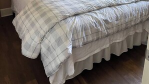 A neatly made bed with a plaid bedspread and pillows, a bedside lamp, and a ceiling fan.