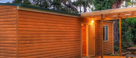 A wooden cabin with a covered porch and a door leading to an interior space.