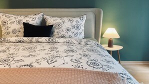 A neatly made bed with floral bedding, a black pillow, and a bedside lamp. - 1.5-room apartment with terrace (Pirna)