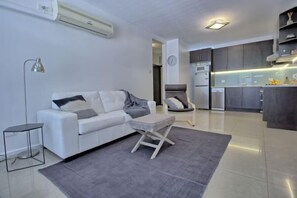 A modern living room with a white sofa, a small table, and a grey rug.