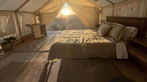 A tented room with a bed, a small table, and a chair. - A Cozy Sunrise Glamping Escape with Panoramic View (Fallbrook)