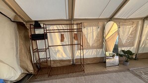 A tent interior with a metal rack, a small table, and a potted plant. - A Cozy Sunrise Glamping Escape with Panoramic View (Fallbrook)