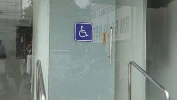 A door with a wheelchair accessibility sign, a metal handrail, and a door handle.