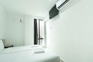 A hotel room with two beds, a flat-screen TV, a window with curtains, and an air conditioning unit. - Grand Bagan Hotel (Butterworth)