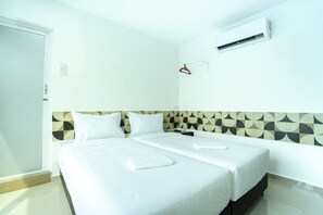 A hotel room with two beds, a wall-mounted air conditioner, and a door. - Grand Bagan Hotel (Butterworth)